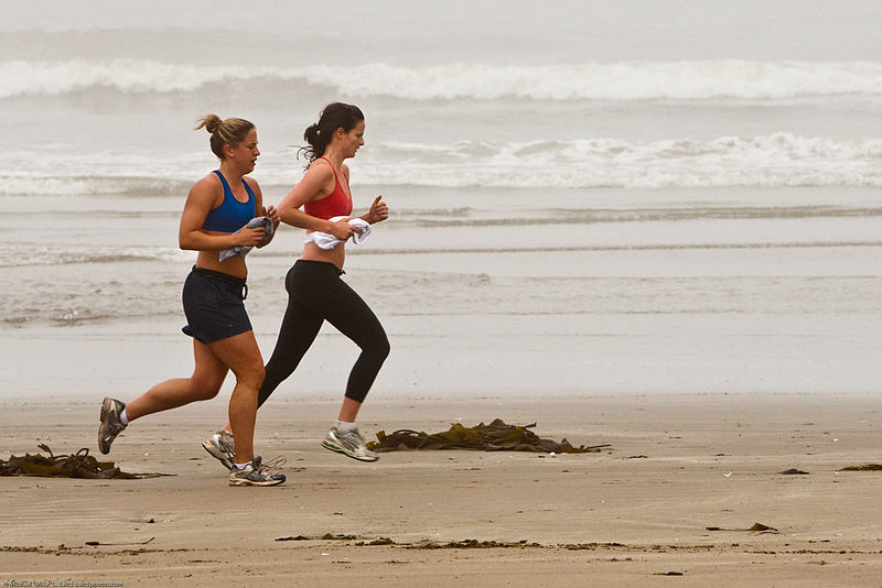Two persons running on a beach.