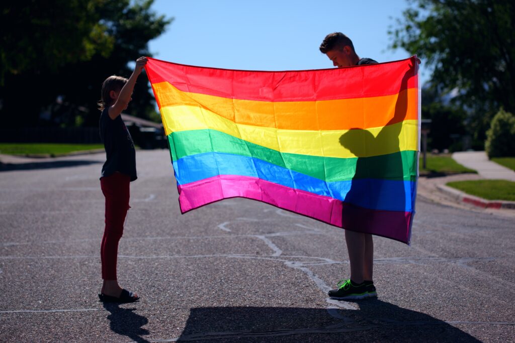 Two persons holding a colorful LGBTQ flag.