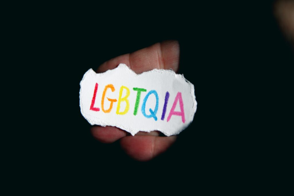 The letters "LGBTQIA" written with colorful ink on a piece or paper.