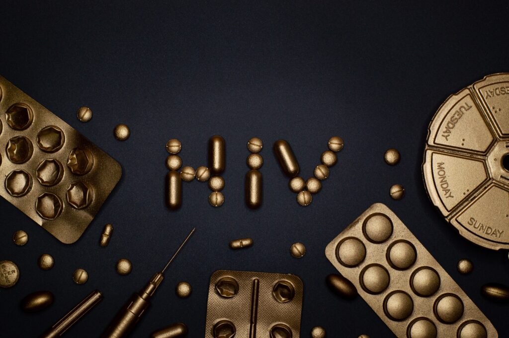 "HIV" spelled out with pills. There is also a pill box and pills coated with gold.