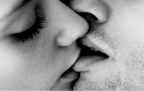 A person kissing and biting their partner's lips.