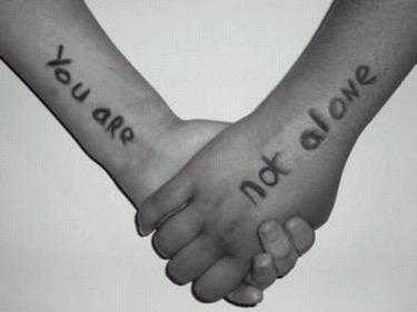 A couple of hands holding each other. One hand reads "you are" and the other reads "not alone."