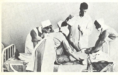 A patient laying on a bed, surrounded by a group of medical professionals.