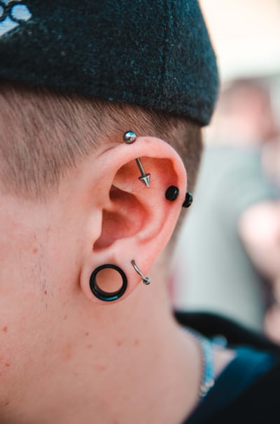 A person's ear with multiple piercings.