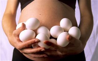 Person holding many eggs around their stomach. 