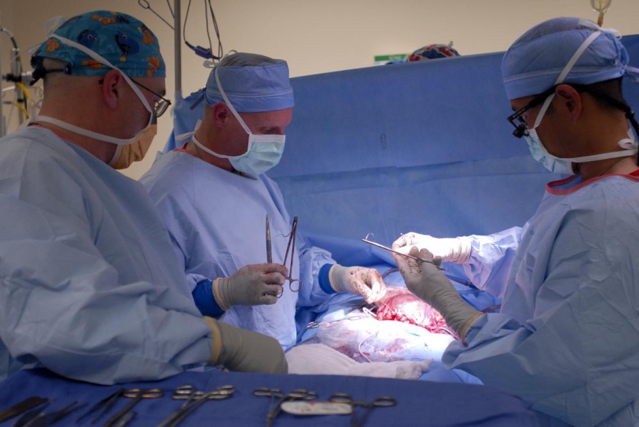 
Three surgeons operating on person's organs