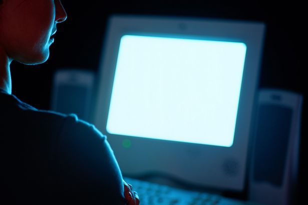 A person starring at a lit up computer screen.