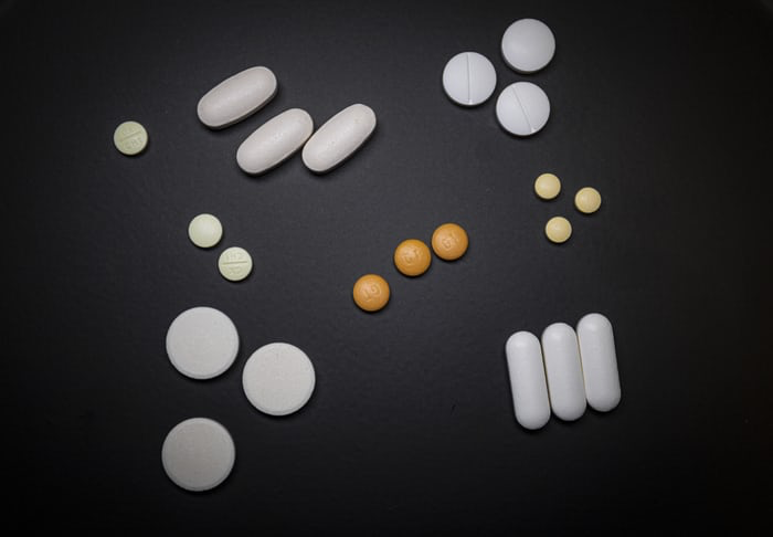 A variety of white and orange pills against a black background.
