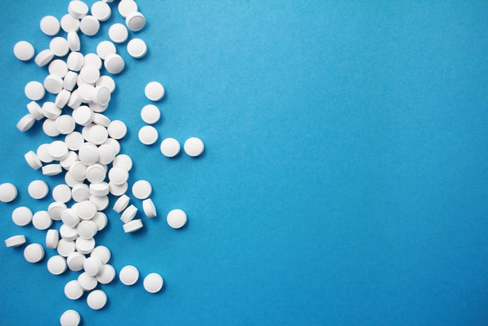 A multitude of white pills against a blue background.