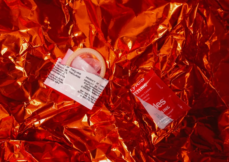 a condom and its open wrapper against a red background