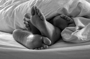 Two people's feet sticking out of the blanket.