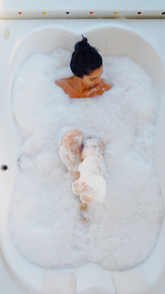 Person submerged in bubbles in their bathtub. 