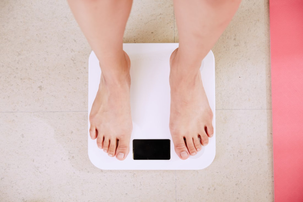 Person standing on a white digital scale with only their legs and the scale visible
