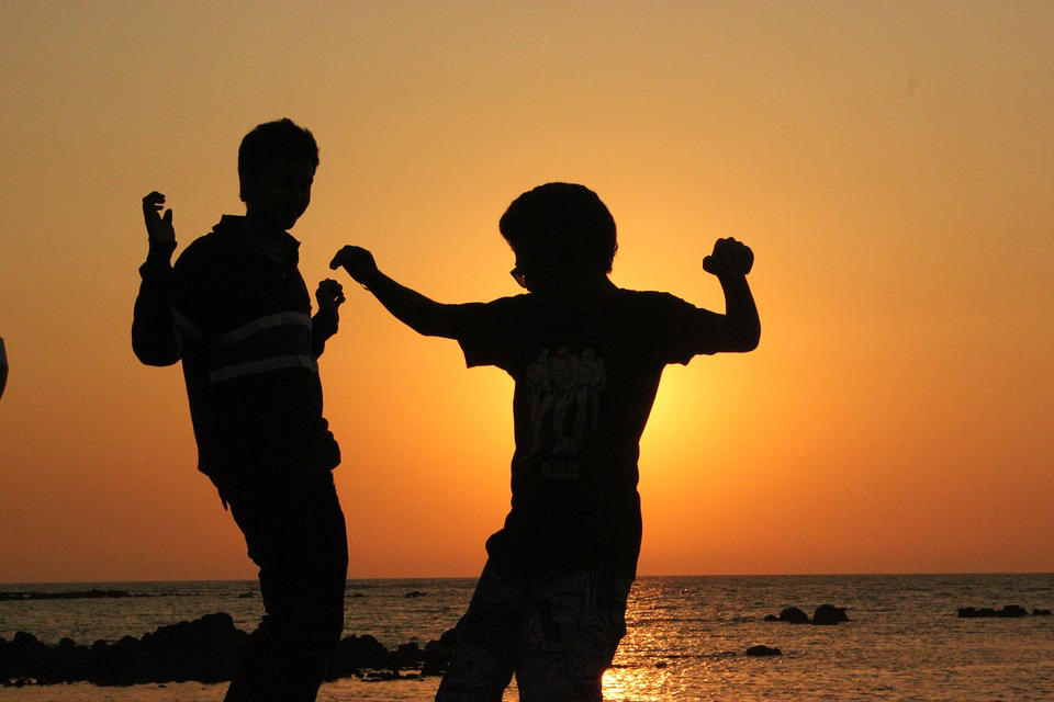 Silhouettes of two men having fun on the beach