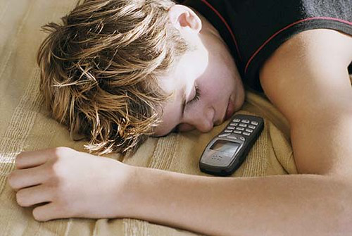 Young man sleeping next to an old phone