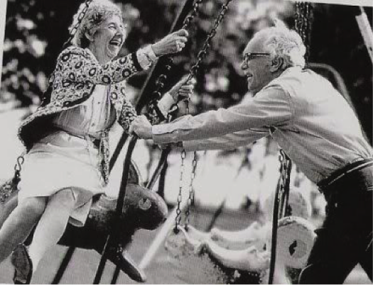 Two elderly people using a swing. 