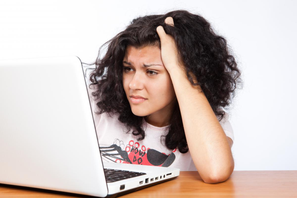 A person starring at a laptop screen, in distress.