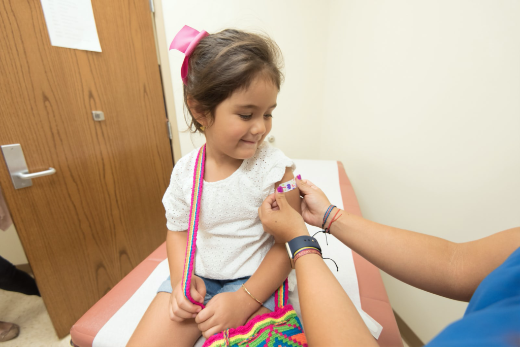 A child getting a bandaid on her arm.