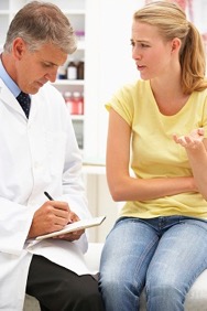 A patient who is talking to a doctor. The doctor is writing on a note pad.