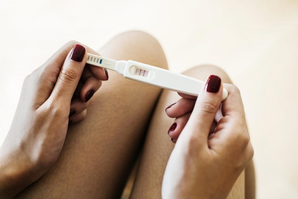A person holding a pregnancy test that has two lines on it.