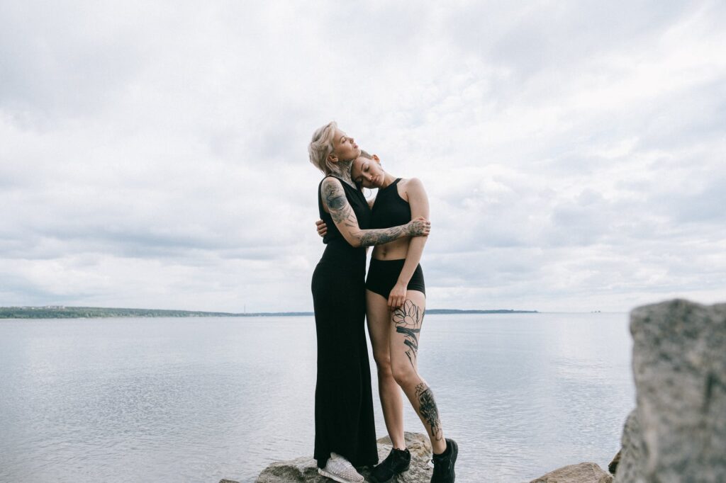 Two persons standing on top of a rock in the ocean, hugging