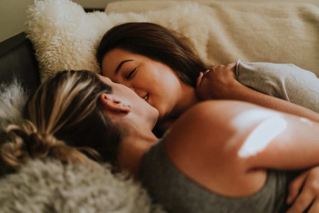 Two women close to each other in bed, about to kiss
