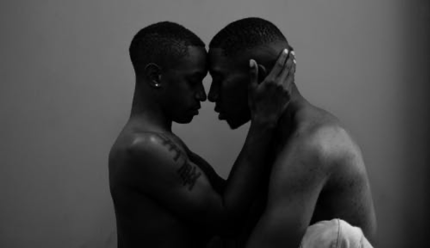 Two shirtless men holding each other closely