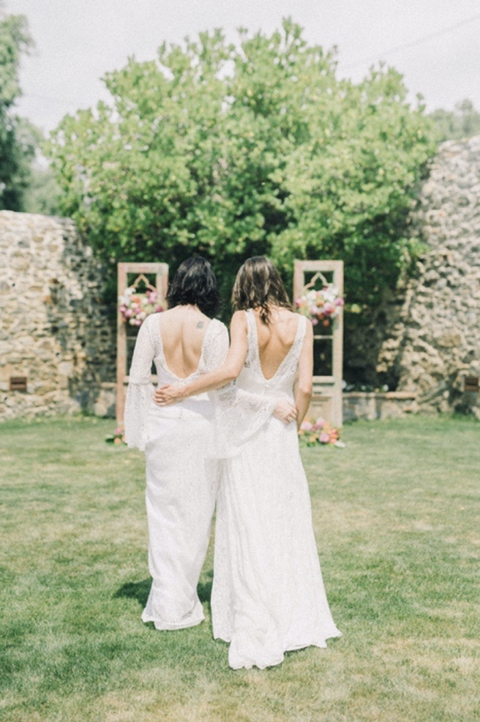 A couple of women wearing wedding dresses and hugging.