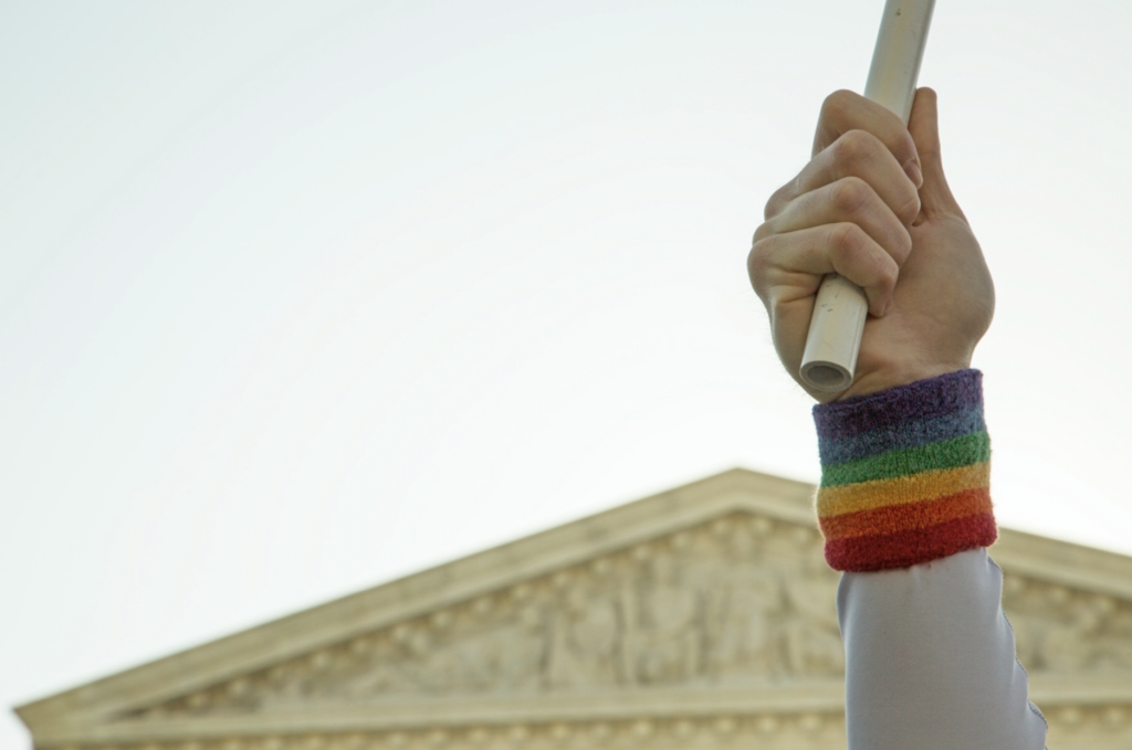 A person holding a stick and wearing a rainbow band on their wrist.