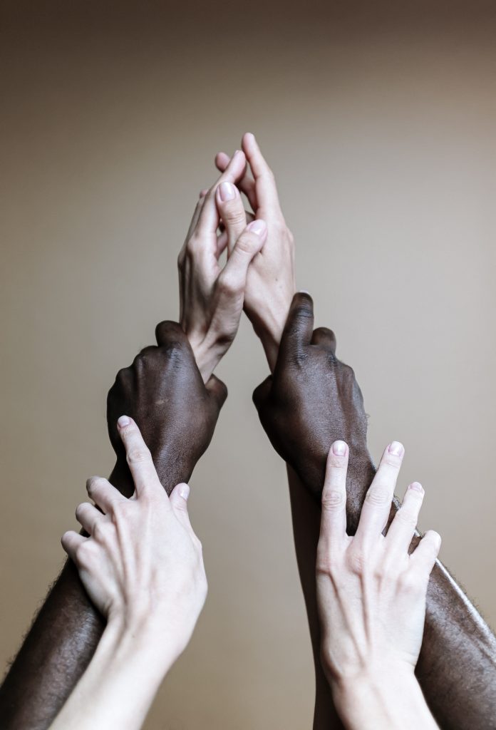 Three pairs of hands holding each other's wrists to form a triangle.