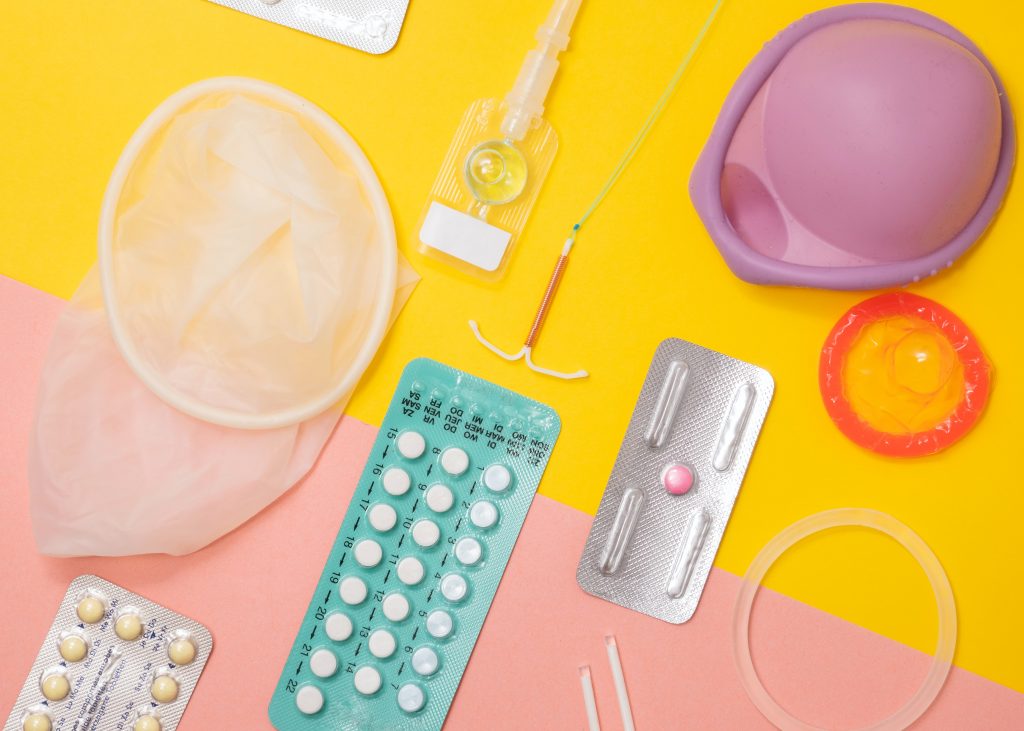A variety of contraceptives: condoms, birth control pills. intrauterine device, arm implant, and vaginal ring.