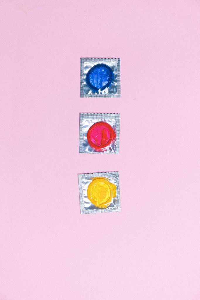 Three condoms: a blue one, a red one, and a yellow one.