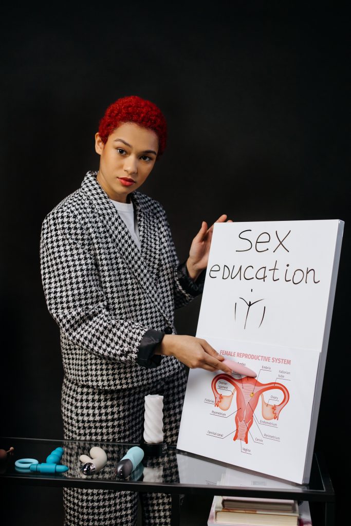 A person holding a sign that says "sex education" and has a diagram of the female reproductive system.