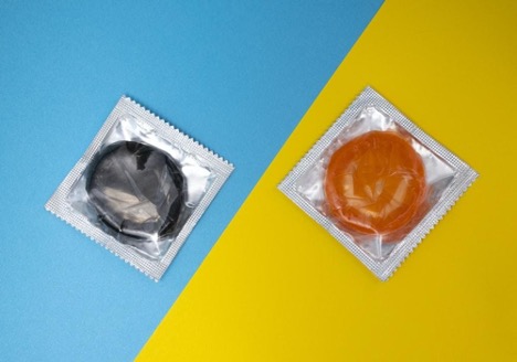 two colored condoms side by side against yellow and blue background