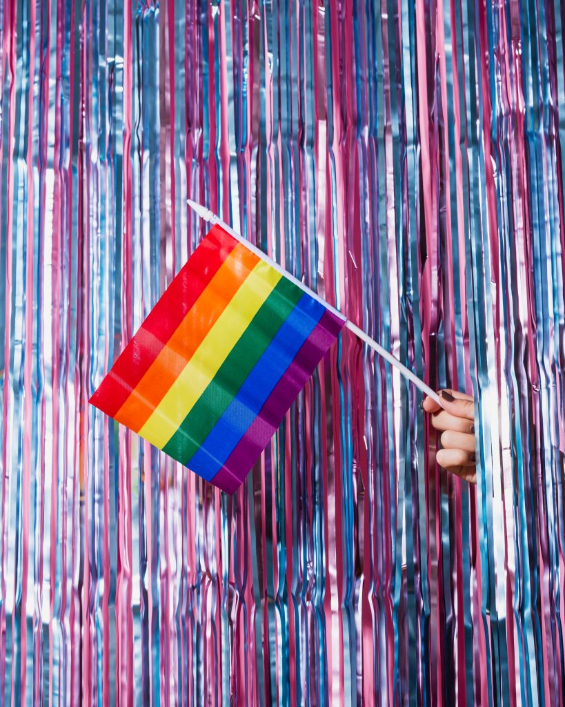 The LGBTQ flag in front of a decorative, colorful backdrop.