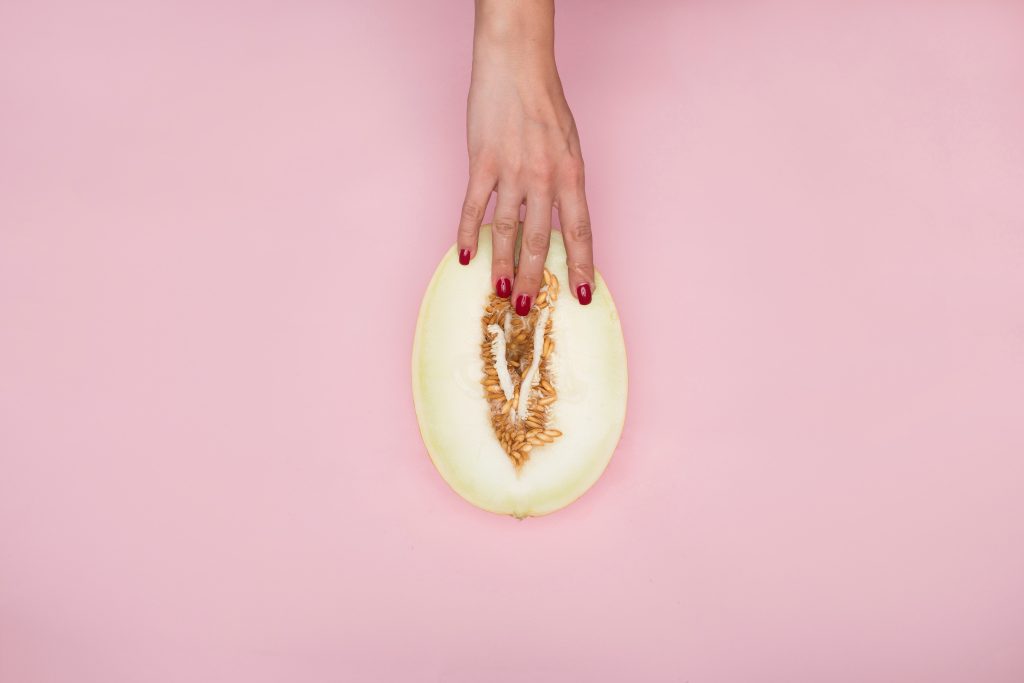 A person's hands fingering a half-cut melon.
