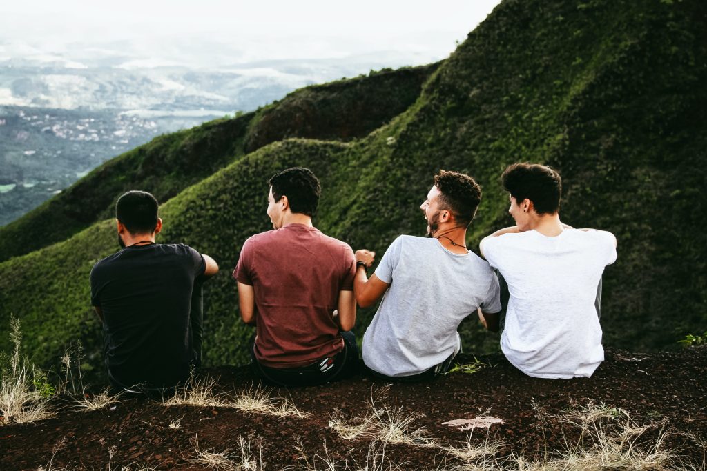 A group of four boys sitting next to each other outside.
