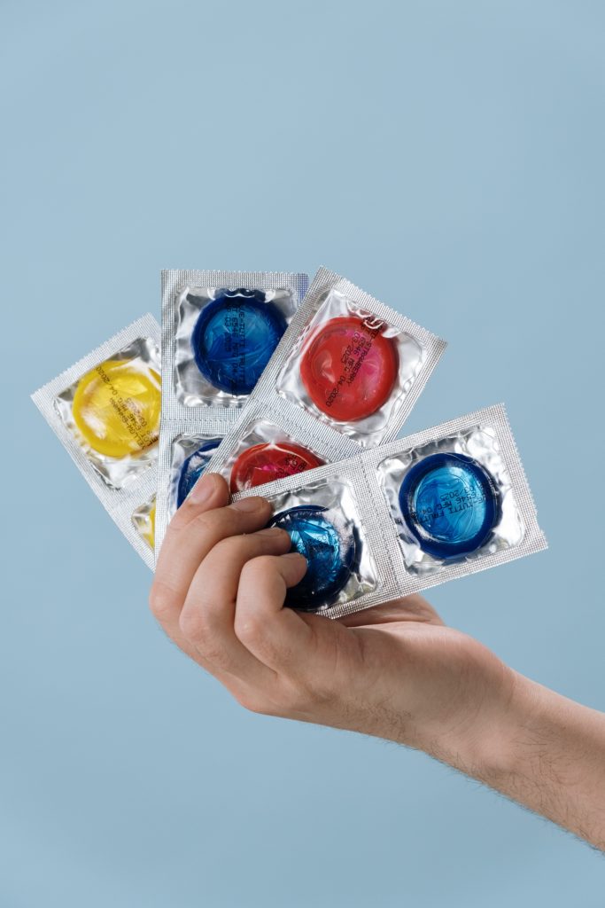 A person holding colorful condoms.