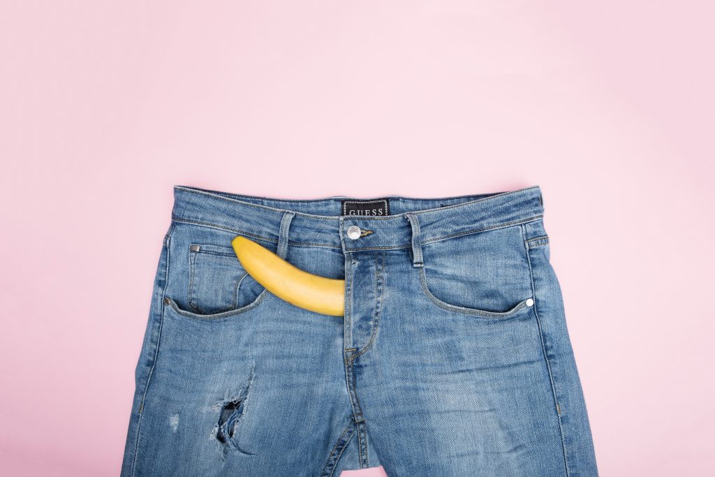 A banana protruding out of the zipper part of a pair of jeans.