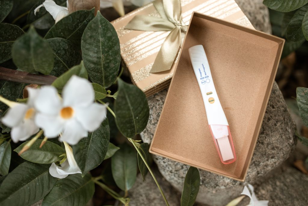 A pregnancy test in a small box, surrounded by flowers.