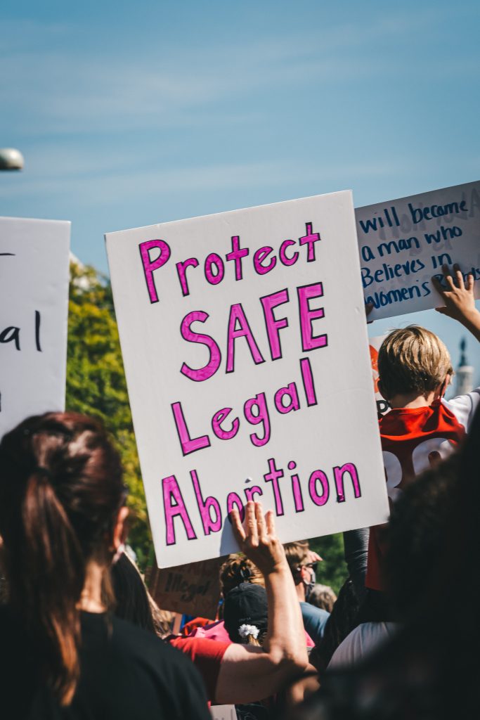 A person holding a poster that says "protect safe legal abortion."