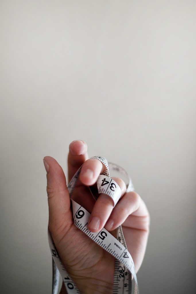 Measuring tape wrapped around a person's hand.