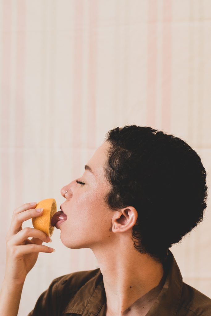A person licking an orange.