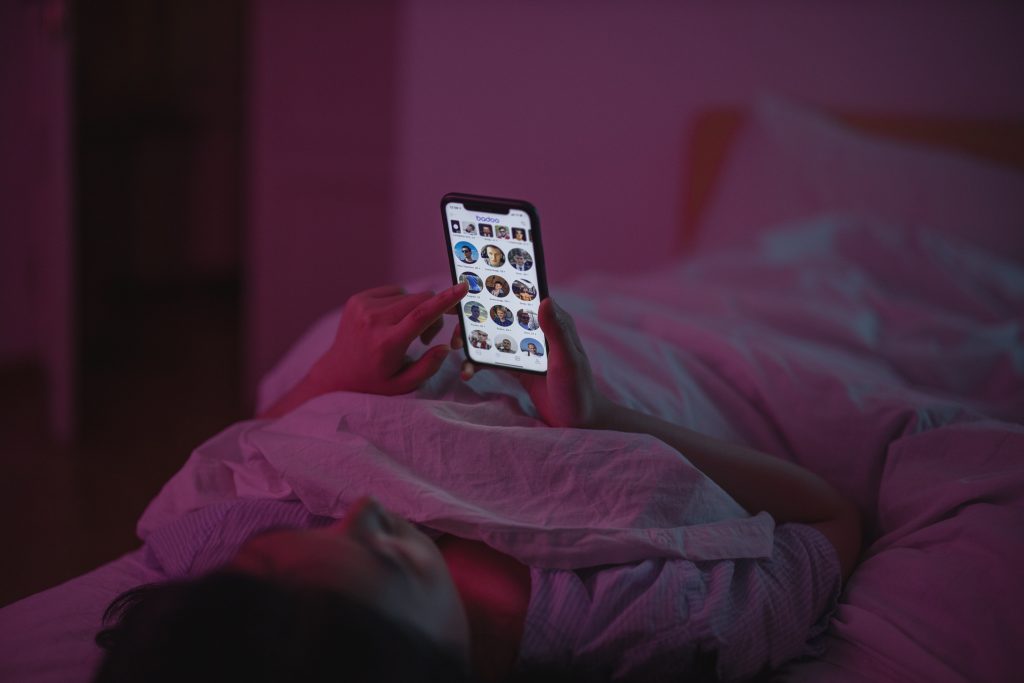 A person laying on a bed, while looking at a phone.