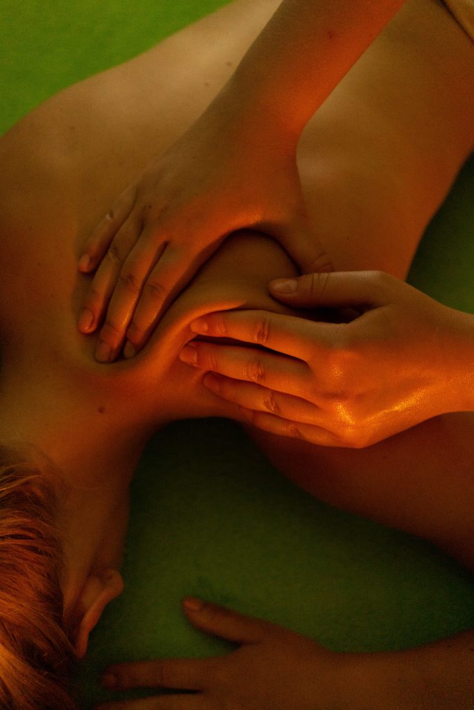 A person laying down topless. Another person is massaging their back.