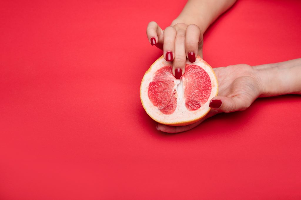 A person "fingering" a half-cut grapefruit.