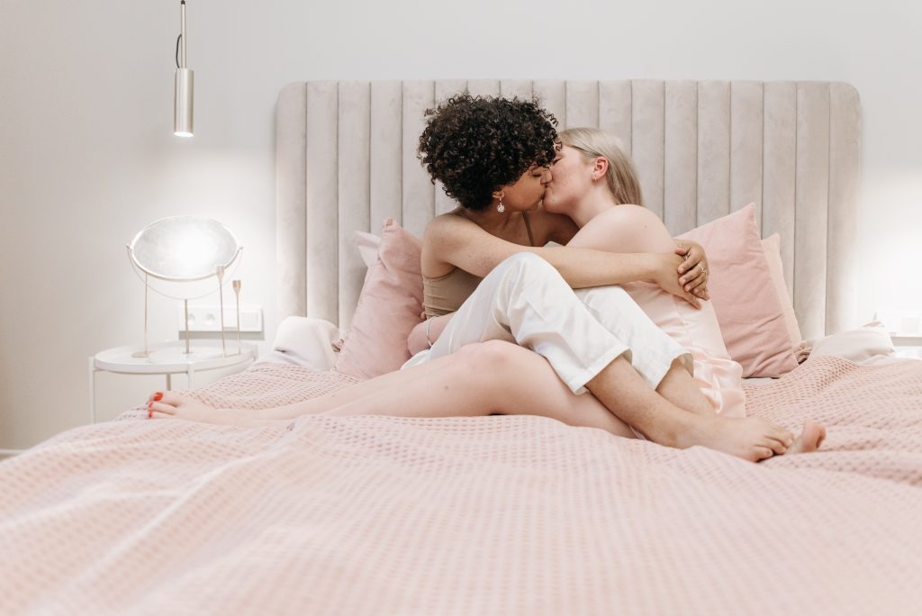A couple kissing on a bed.