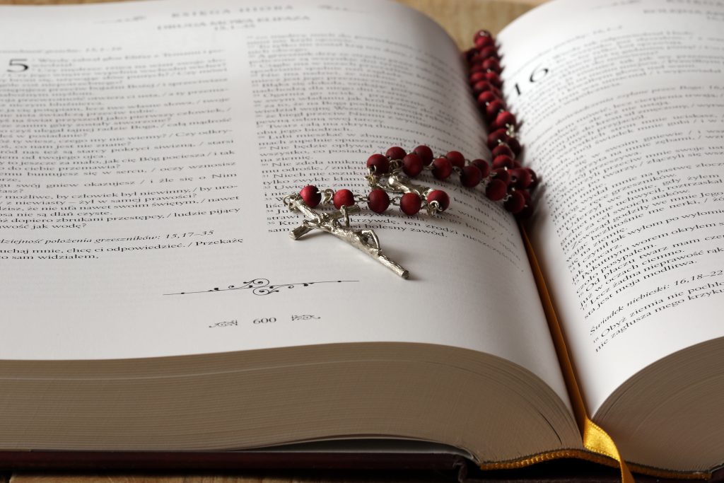 A rosary on top of an opened bible.