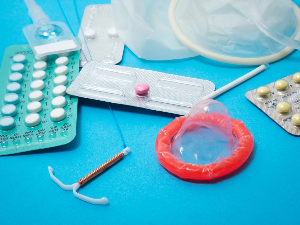 A variety of contraceptive methods, including a condom, intrauterine device, birth control pills, and arm implant.