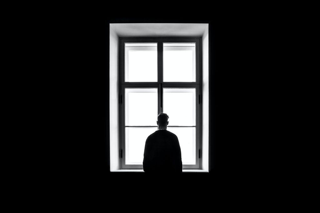 A person facing a large window.